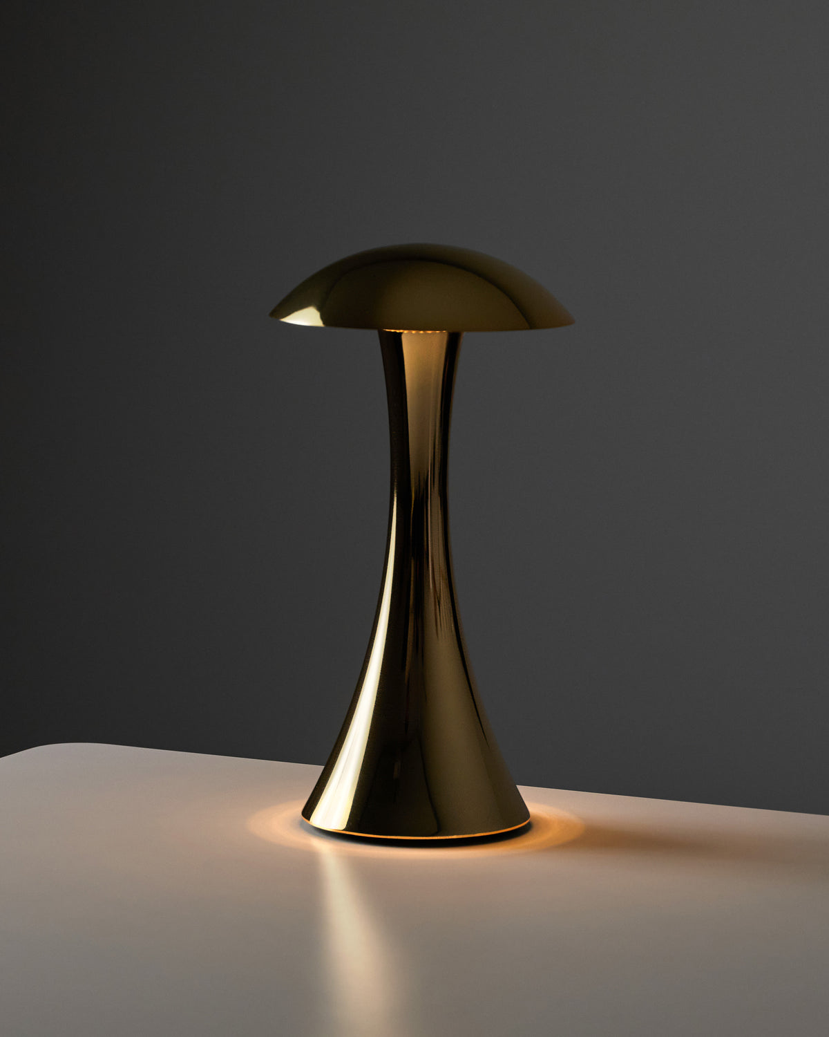 NEOZ Nimbus Gold Chrome Cordless Lamp glowing on a tabletop, designed by James Perry and made in Australia